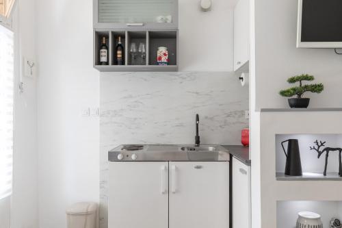 a kitchen with white cabinets and a sink at Apartment Modern Studio Near Žnjan Beach in Split