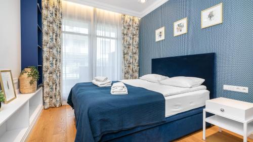 niebieska sypialnia z łóżkiem i oknem w obiekcie Prestige Apartments Neptun Park w Gdańsku