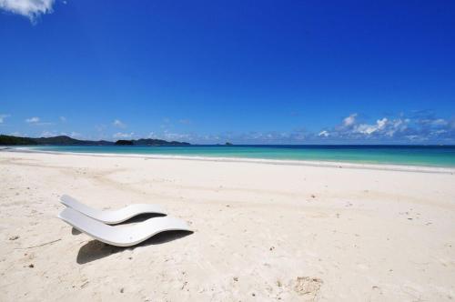 a white chair sitting on a sandy beach at Cote d'Or Footprints in Baie Sainte Anne