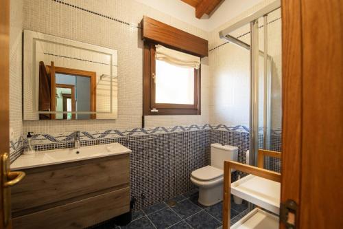 Un baño con lavabo, inodoro y espejo. en Villa La Marquesa de Llanes, en Llanes