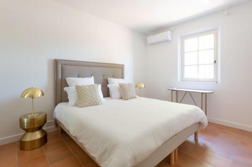 biała sypialnia z dużym białym łóżkiem i oknem w obiekcie VILLA NIKKi w Saint-Tropez