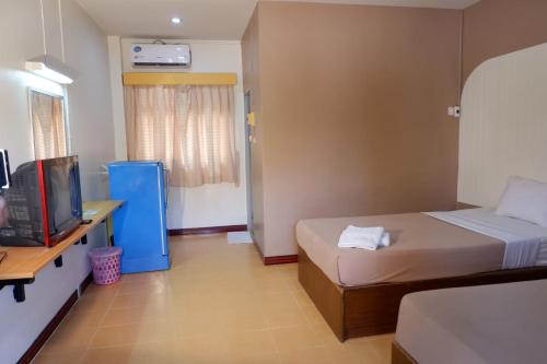 a bedroom with a bed and a desk and a television at กิจตรงวิลล์ รีสอร์ท Kittrongvill in Ubon Ratchathani