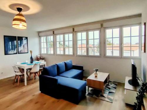 un salon avec un canapé bleu et une table dans l'établissement Appartement familial lumineux, à La Rudelière