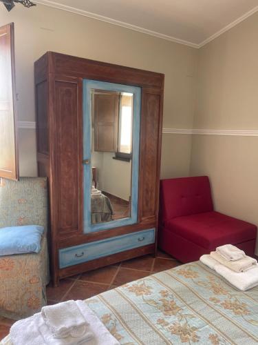 ein Schlafzimmer mit einem Spiegel, einem Stuhl und einem Bett in der Unterkunft Azienda agrituristica Di Fiore in Morcone