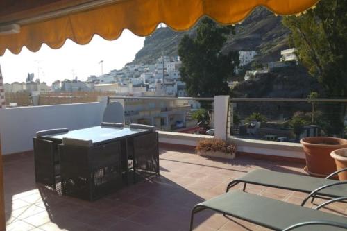 a balcony with a table and chairs and a mountain at Paraíso con gran solarium privado en playa Mogán in Puerto de Mogán