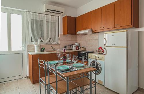 a kitchen with a table and a white refrigerator at Basiliki's Apartments in Archangelos