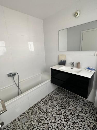 ein Badezimmer mit einer Badewanne, einem Waschbecken und einem Spiegel in der Unterkunft דירת פאר על הים VIP apartment near the beach in H̱adera