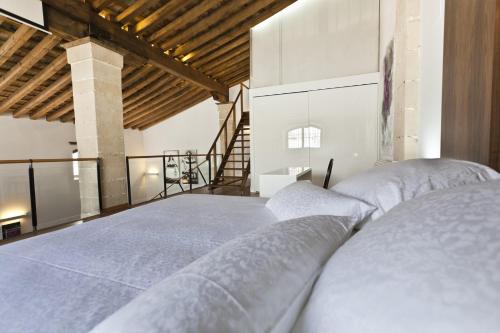 1 dormitorio con 1 cama grande con sábanas blancas en Dúplex tipo Loft con piscina, en Jerez de la Frontera