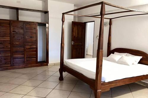 una camera con letto a baldacchino in legno e lenzuola bianche di Mombasa at your doorstep! a Mombasa