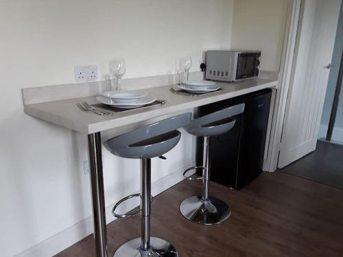 a kitchen counter with two stools and a microwave at Woodside ..Peaceful 1 bedroom ground floor lodge in Louth