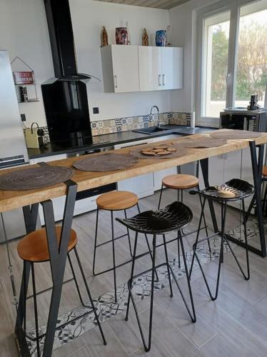 une cuisine avec un grand comptoir en bois avec des tabourets dans l'établissement LES PIEDS DANS L'EAU, à Palavas-les-Flots