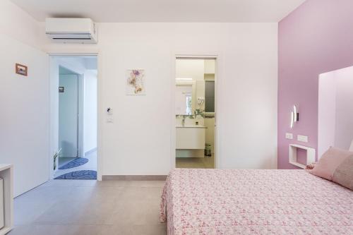 a white bedroom with a bed and a bathroom at Le Rondinelle Rooms in Procida