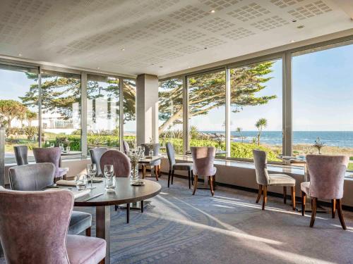 un ristorante con tavoli e sedie e vista sull'oceano di Sofitel Quiberon Thalassa sea & spa a Quiberon