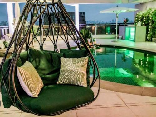 un columpio verde con 2 almohadas frente a la piscina en Hotel GRAND M-RCURE Itaim BiBi - Black Edition - Master Deluxe Duplex - King Studio Veranda - Dream Theater - By LuXXoR en São Paulo