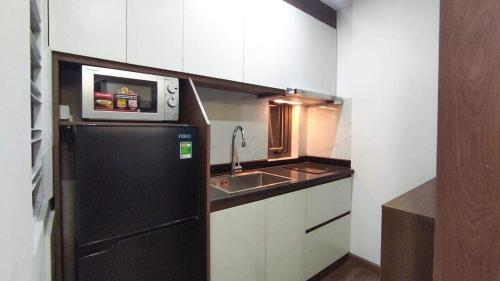 uma pequena cozinha com um frigorífico preto e um lavatório em Candy Home em Hanói