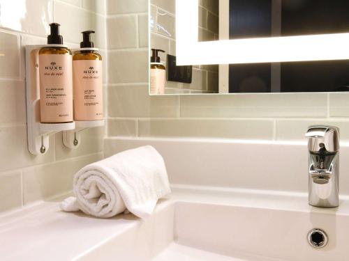 a bathroom with a sink and two bottles of soap at Mercure Arras Centre Gare in Arras