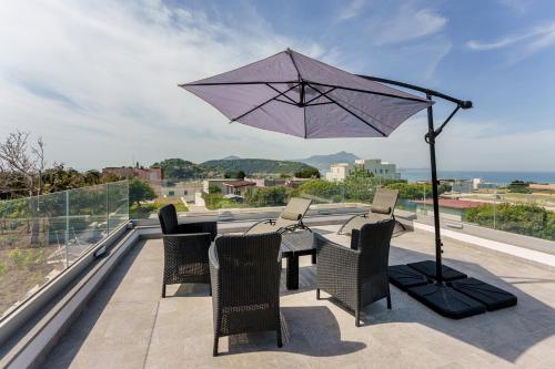 a table and chairs with an umbrella on a balcony at Le Rondinelle Rooms in Procida