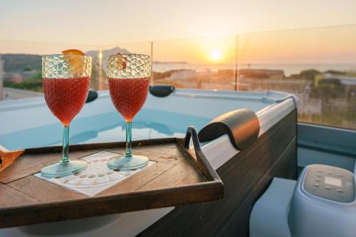 two wine glasses sitting on a table next to a pool at Le Rondinelle Rooms in Procida