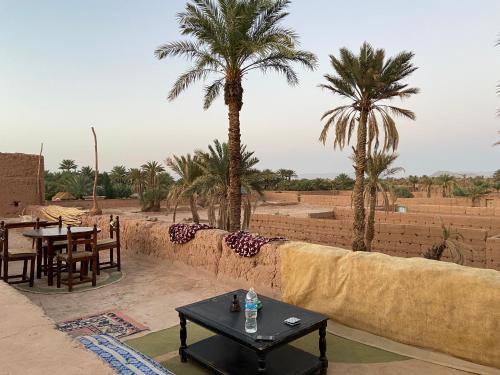 d'une terrasse avec une table et deux palmiers. dans l'établissement Dar Toda - Zagora guest house, à Zagora