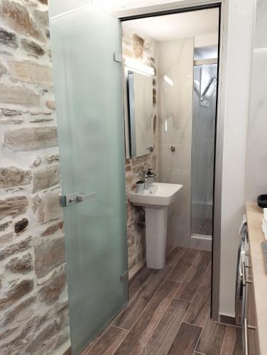 ein Bad mit einem Waschbecken und einer Glastür in der Unterkunft Tsonos Home in Keramídhion