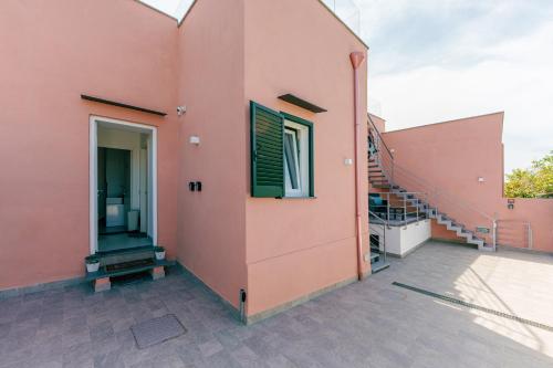 a pink house with a staircase on the side at Le Rondinelle Rooms in Procida