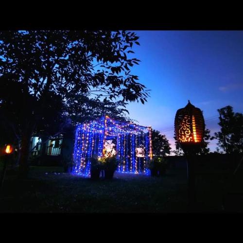 a house decorated with lights in a yard at night at Pernjai Homestay in Pua