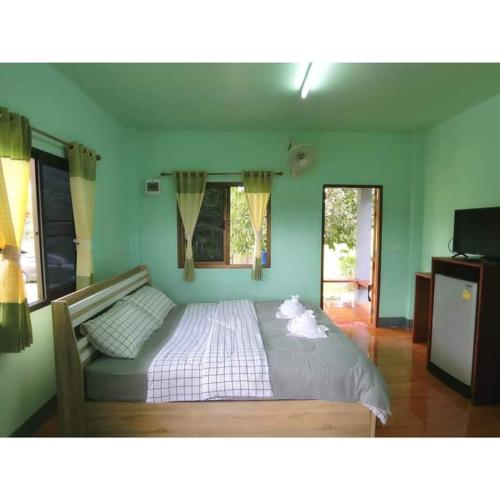 a large bed in a bedroom with green walls at Pernjai Homestay in Pua