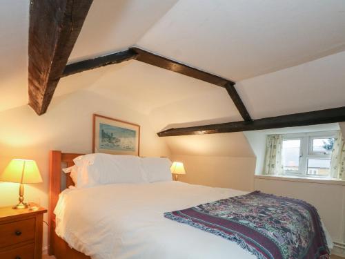 a bedroom with a white bed and a window at Poppy Cottage in Beaminster