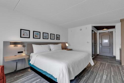 a bedroom with a large white bed and a desk at Hilton Garden Inn Myrtle Beach/Coastal Grand Mall in Myrtle Beach