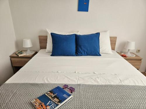 a bed with blue pillows and a book on it at Apartman Sara-Vis in Vis