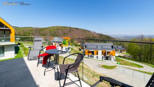 a balcony with a table and chairs and a house at Wonder Home - Domki Hillside tuż przy stoku narciarskim - na terenie kompleksu plac zabaw i zewnętrzna siłownia, sklep, parking in Karpacz