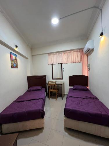 a bedroom with two beds and a table with a chair at Wave & Sea Homestay in Port Dickson