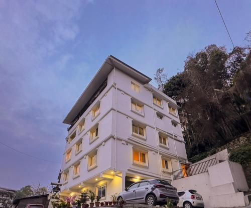 een wit gebouw met auto's ervoor geparkeerd bij Hotel Sherabling in Gangtok