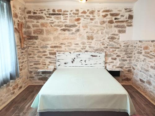 a bed in a room with a stone wall at Tsonos Home in Keramídhion