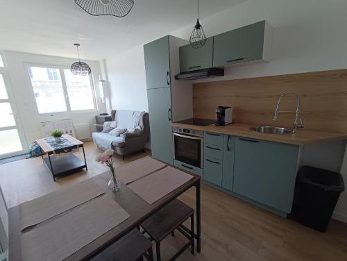 Il comprend une cuisine et un salon avec une table. dans l'établissement L'olivier Maison de ville proche Cabourg, à Dozulé
