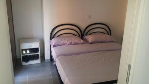 リミニにあるAppartamento Santa Margheritaのベッドルーム1室(ピンクの枕が付いたベッド1台付)