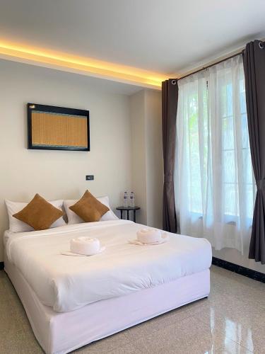 a white bed in a room with a window at Flora Hostel KhaoSok in Khao Sok