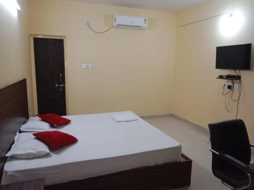a bedroom with a bed and a tv and a chair at Goroomgo Green Akress Bhubaneswar in Bhubaneshwar