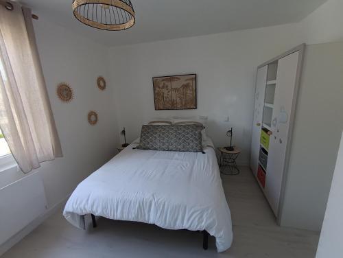 une chambre avec un lit dans une pièce blanche dans l'établissement L'olivier Maison de ville proche Cabourg, à Dozulé