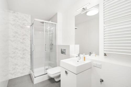 a white bathroom with a sink and a shower at Symphony City Square Aparthotel in Wrocław