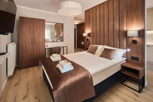 a bedroom with a large bed with two towels on it at Symphony City Square Aparthotel in Wrocław