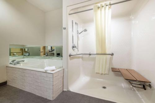 a white bathroom with a tub and a sink at Sleep Inn & Suites Green Bay South in De Pere