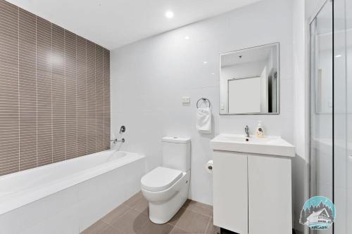 a white bathroom with a toilet and a sink at Aircabin - Mascot - Walk to Station - 2 Beds Apt in Sydney
