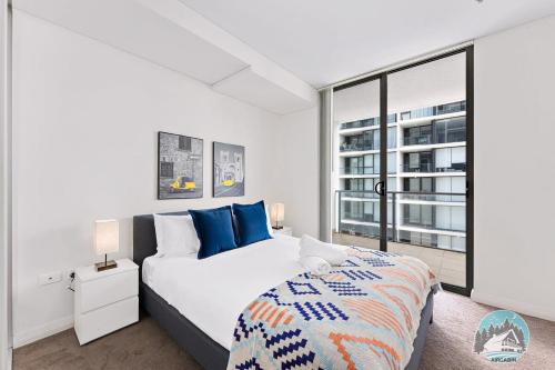 a white bedroom with a large bed and a window at Aircabin - Mascot - Walk to Station - 2 Beds Apt in Sydney