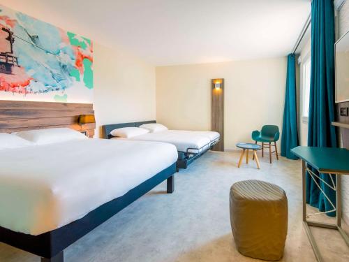 サランシュにあるIbis Styles Sallanches Pays du Mont-Blancのベッド3台とテーブルが備わるホテルルームです。