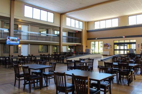 an empty cafeteria with tables and chairs and windows at Ramada by Wyndham North Platte in North Platte