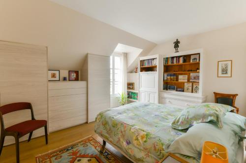 ein Schlafzimmer mit einem Bett, einem Stuhl und Bücherregalen in der Unterkunft Maison avec terrasse privée in Versailles