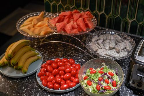 a table topped with plates of fruits and vegetables at Lan Wan Hotel - Next to Huangsha Metro St ation -One cup of Free Cockt ail or Harbin Beer Per Room--Cha rgeable Airport Pick-up Service in Guangzhou