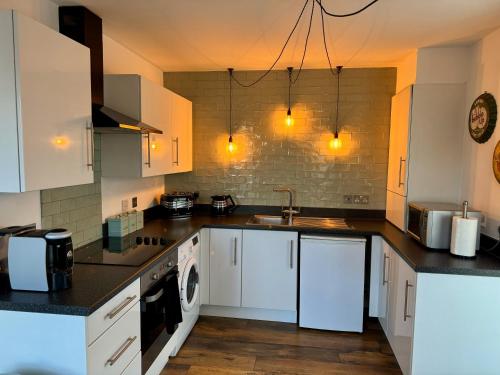 a kitchen with white cabinets and a sink at LUXURY spacious apartment next to Chester train station 10 min walk to Chester city center FREE parking The Old Post Office Apartment by Rework Accommodation in Chester