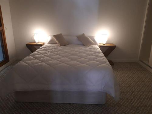 1 dormitorio con 1 cama blanca grande y 2 lámparas en Rincón en edificio Modernista en centro de Soria, en Soria